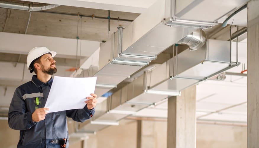 Technicien inspectant des gaines de ventilation CVC sur chantier, en vue du réemploi des équipements techniques