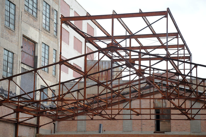 Charpente métallique et murs en brique d'un ancien bâtiment industriel en réhabilitation, structure conservée pour le réemploi