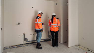 Deux consultants Citae, vus de dos, examinent une cloison dans un logement en chantier