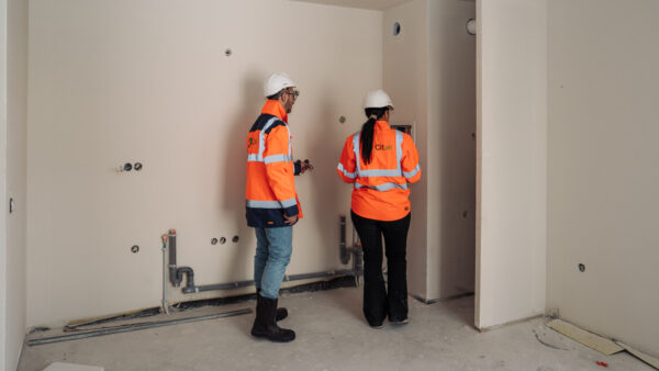 Deux consultants Citae, vus de dos, examinent une cloison dans un logement en chantier