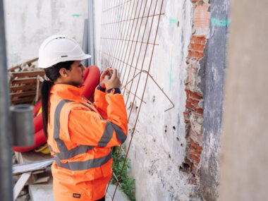 Un consultant Citae, vu de dos, photographie les cloisons d'un couloir en chantier